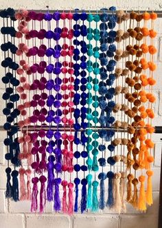 a multicolored wall hanging with tassels and pom - poms