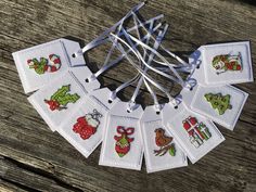 small cross stitch tags are arranged on a wooden table with string attached to the strings