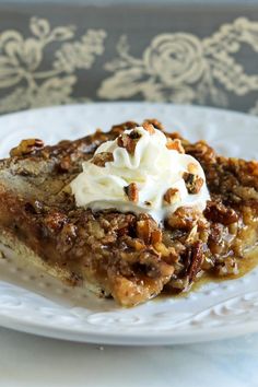 a piece of pecan pie on a white plate with whipped cream and pecans