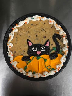 a cake decorated like a black cat sitting on top of a pumpkin with sprinkles