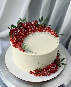 a white cake decorated with berries and greenery