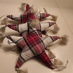 three plaid pillows with tassels are arranged in the shape of an upside down star