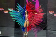 a woman is walking down the runway in a colorful costume