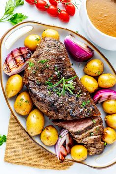 steak, potatoes and tomatoes on a plate next to a cup of coffee with sauce