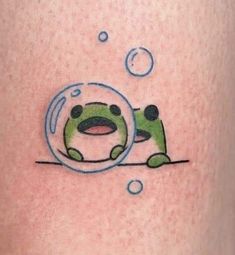 a tattoo with a green frog in a bubble