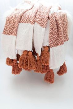 two towels with tassels on them sitting next to each other in front of a white background