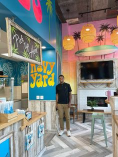 a man standing in the middle of a room with colorful walls and wood flooring