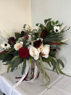 a vase filled with flowers sitting on top of a white table cloth covered tablecloth