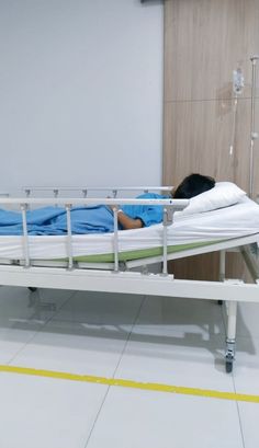 a person laying on a hospital bed in a room