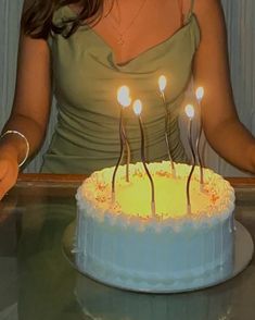 a woman sitting in front of a cake with lit candles