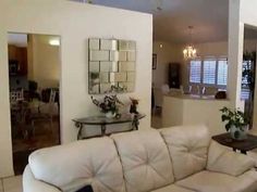 a living room filled with white furniture and lots of mirrors on the wall above it