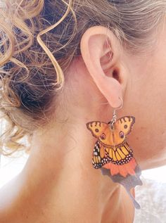 a close up of a person wearing earrings with a butterfly on it's ear