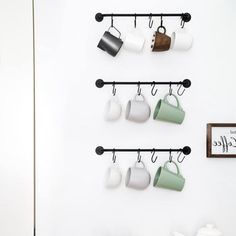 coffee cups are hanging on the wall with hooks