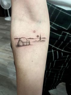 a person with a small tattoo on their arm that has a lighthouse in the distance