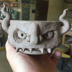 a hand holding a clay sculpture of a monster's head