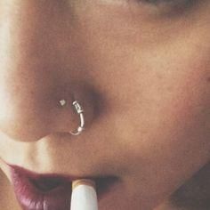 a close up of a person with a nose ring on their left side, wearing an earring