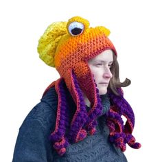 a woman wearing a knitted hat with an orange and purple octopus on it's head