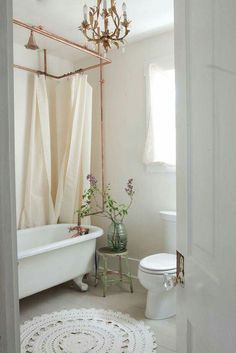 a bathroom with a white bath tub sitting next to a toilet under a chandelier