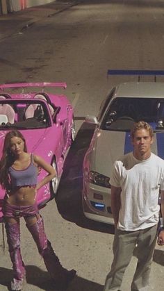 two people standing next to a pink car