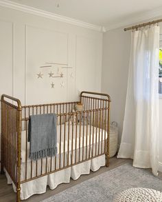 a baby's crib in the corner of a room with white walls and curtains