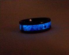 "This ring is beautiful and understated in the indoor light and becomes a feast for the eyes when viewed in the sunshine or bright light. It is made of black ceramic with an inlay that includes blue lapis lazuli, purple amethyst, obsidian and mother of pearl (among other things). I use the same inlay for this ring as the inlay in my blackened cherry \"galaxy\" ring for those who need something more durable than wood. This ring is 8mm wide with a 4mm inlay channel. This ring also glows in the dar Glow In The Dark Black Jewelry For Gift, Galaxy Ring, Black Rings, Purple Amethyst, Indoor Lighting, Lapis Lazuli, Mother Of Pearl, Wedding Bands, Amethyst