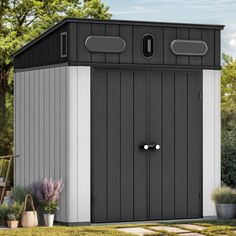 a black and white shed sitting in the grass