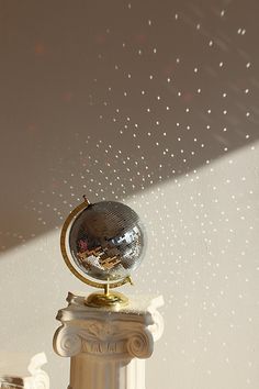 a silver globe sitting on top of a white pillar