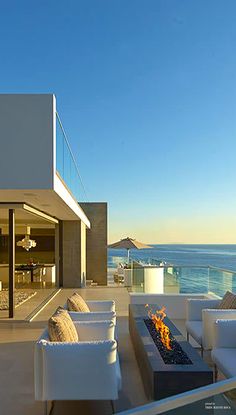 an outdoor living area with couches and fire pit on the deck overlooking the ocean