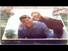 a man and woman are posing in front of a photo on a table with flowers