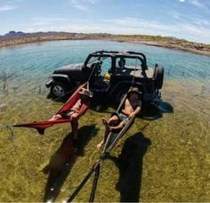 two canoes are in the water next to an old jeep that has been pulled over