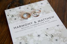 two wedding rings sitting on top of a piece of paper with the words harmony and mathew