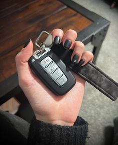 a person holding a car key in their left hand and a remote control in the other hand