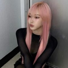 a woman with pink hair sitting on the floor in front of a wall and wearing black stockings