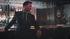 a man in a suit and tie standing next to a bar