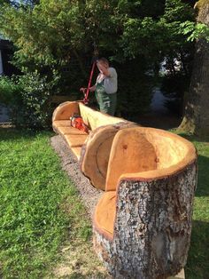 a man standing on top of a wooden bench next to a tree stump in the grass