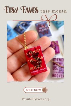 a hand holding a small red book necklace