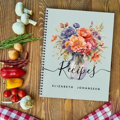 a recipe book sitting on top of a wooden table next to fresh vegetables and garlic