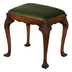 an antique wooden stool with green velvet upholstered seat and foot rests on white background