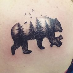 a bear and birds tattoo on the back of a woman's shoulder