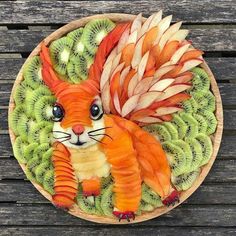 a plate that has some fruit on it and a cat made out of kiwis