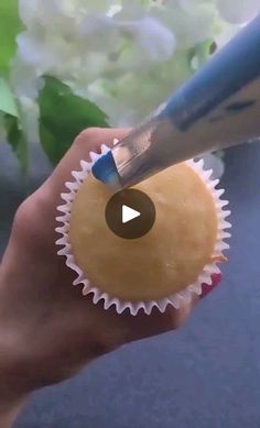 a person is holding a cupcake with a knife in it