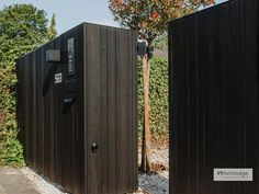 two black portable toilets sitting next to each other on top of a gravel covered ground