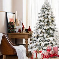 a white christmas tree in a living room with presents on the floor next to it