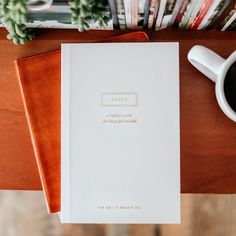 a book sitting on top of a wooden table next to a cup of coffee