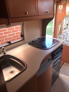 a kitchen area with sink, stove and cabinets in an rv's living room