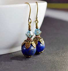 "Victorian Aqua & Lapis Earrings - Lapis Lazuli Earrings - Aquamarine Swarovski Crystals . . . Lapis Lazuli is my favorite gemstone. Lapis is gorgeous when set in sterling silver or gold filled but fabulous in antique gold brass. These stunning handmade Victorian Lapis Earrings come in vibrant, and vivid deep blue hues accented with aquamarine and antique brass. Artisan created blue lapis earrings featuring polished round lapis gemstones topped in genuine Swarovski Elements, bicone shaped aq Lapis Jewelry, Beaded Necklace Patterns, Lapis Earrings, Artisan Jewelry Handmade, Lapis Lazuli Earrings, Brass Beads, Necklace Patterns, Blue Stones, Aquamarine Crystal