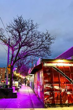 there is a purple light on the street in front of some buildings and a tree