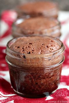 three jars filled with chocolate pudding sitting on top of a red and white table cloth