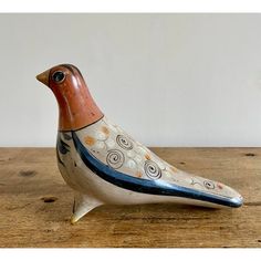 a ceramic bird sitting on top of a wooden table