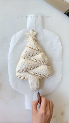 a person is decorating a christmas tree on a cutting board with a knife and paper towel